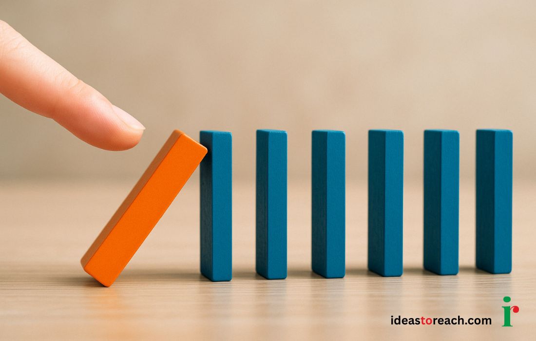 A hand gently pushing an orange domino to trigger a row of blue dominoes, symbolizing how one strategic SEO action can lead to a chain reaction of growth and visibility.